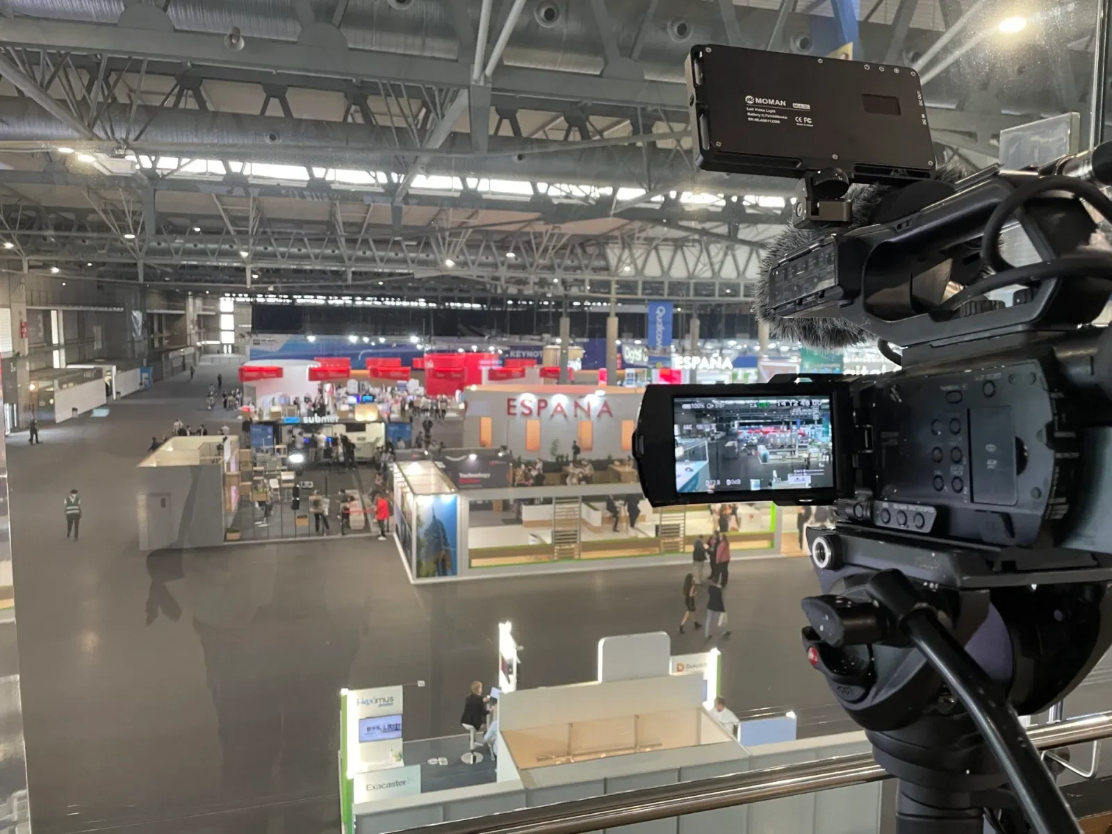 Trade fair videographer filming an exhibition hall in Barcelona with a camera and monitor