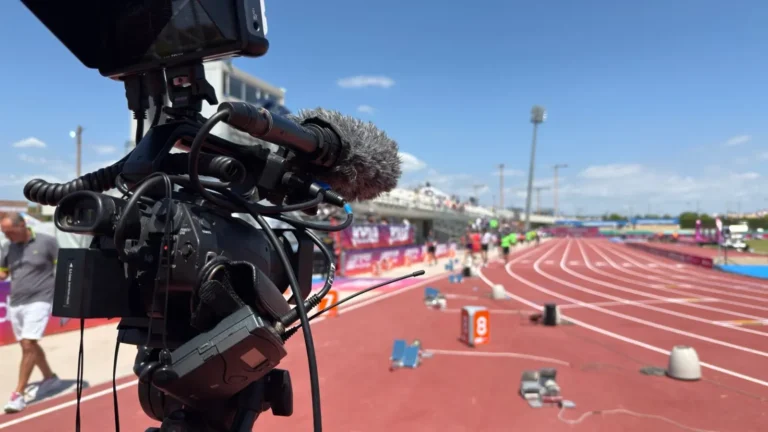 Cámara de vídeo con micrófono grabando en una pista de atletismo al aire libre