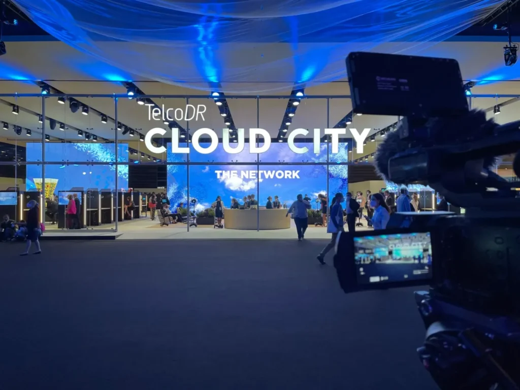Videographer filming a stand lit in blue at a technology trade fair in Barcelona
