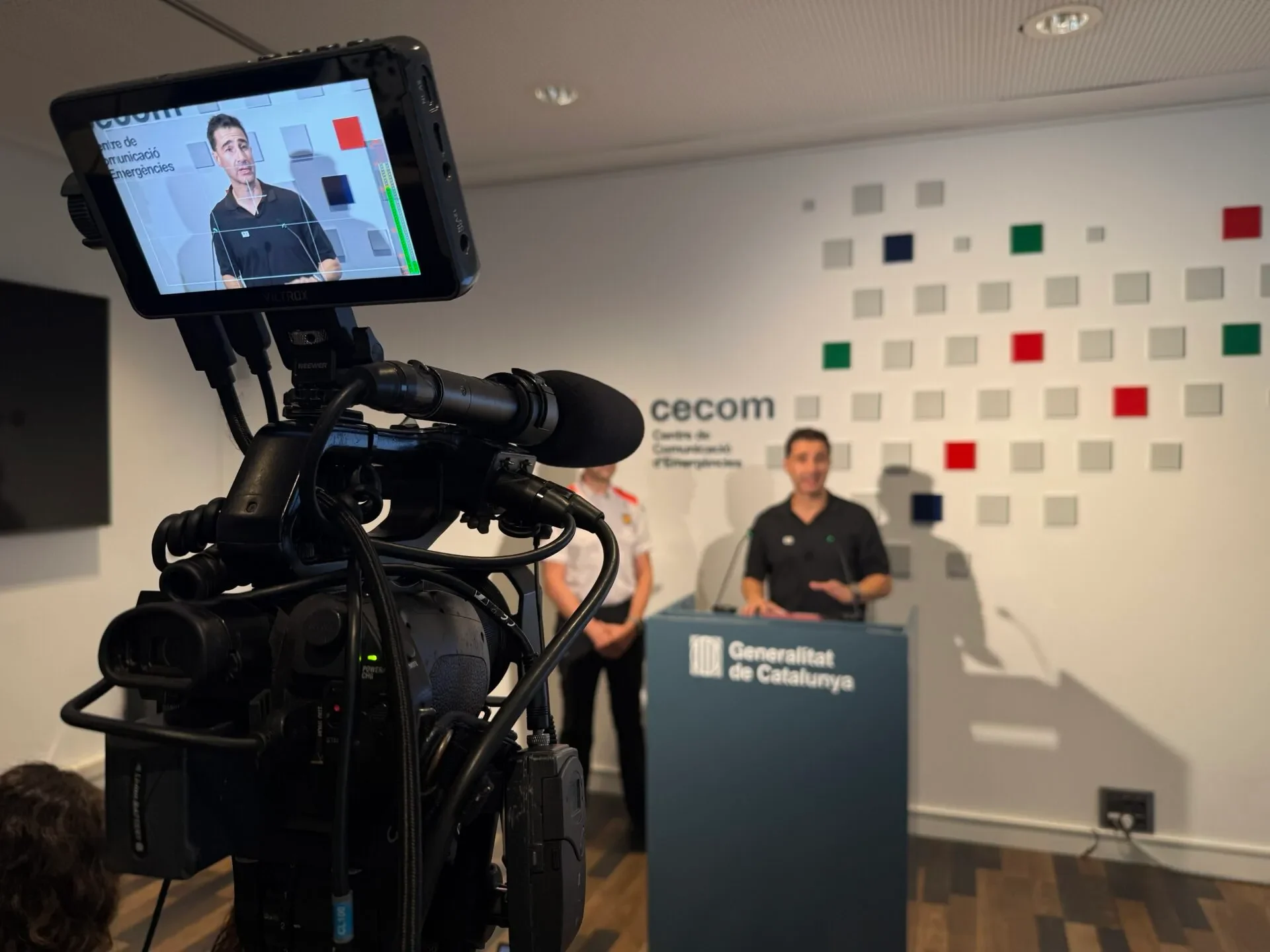 Cámara de vídeo profesional grabando una rueda de prensa, con el monitor mostrando al orador en el atril
