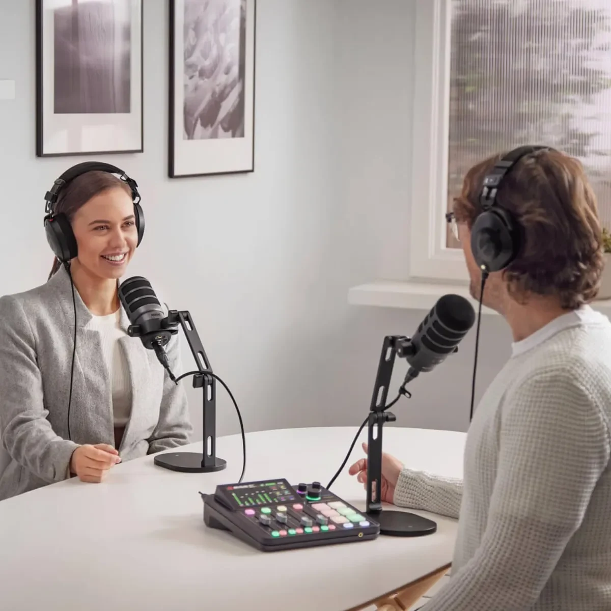 Dos personas grabando un videopodcast con auriculares y micrófonos sobre una mesa con mesa de mezclas